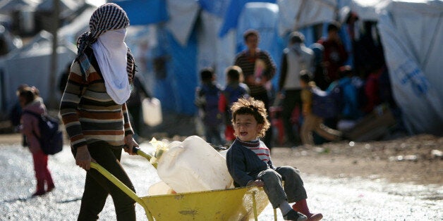 A Syrian-Kurdish refugee carries water containers on a wheelbarrow at the Quru Gusik (Kawergosk) refugee camp, 20 kilometers east of Arbil, the capital of the autonomous Kurdish region of northern Iraq, on December 29, 2013. The fighting in Syria pushed tens of thousands of Syrian Kurds across the border into Iraqi Kurdistan, which the United Nations says now hosts more than 203,000 Syrian refugees, the vast majority of those in Iraq. AFP PHOTO / SAFIN HAMED (Photo credit should read SAFIN HAMED/AFP/Getty Images)