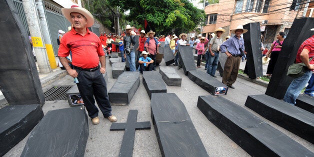 Members of the Peasant Unified Movement (MUCA) of Bajo Aguan, carry mock coffins bearing pictures of murdered mates in land conflict clashes, during a march commemorating the country's 191st independence anniversary, in Tegucigalpa, on September 15, 2012. AFP PHOTO/Orlando SIERRA (Photo credit should read ORLANDO SIERRA/AFP/GettyImages)