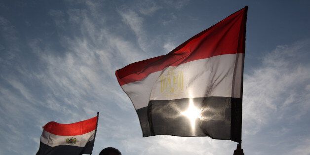 CAIRO, EGYPT - JANUARY 30: Men in Tahrir Square hold Egyptian flags on January 30, 2011 in Cairo, Egypt. As President Mubarak struggles to regain control after five days of protests he has appointed Omar Suleiman as vice-president. The present death toll stands at 100 and up to 2,000 people are thought to have been injured during the clashes which started last Tuesday. Overnight it was reported that thousands of inmates from the Wadi Naturn prison had escaped and that Egyptians were forming vigilante groups in order to protect their homes after Police were nowhere to be seen on the streets. Broadcasts from the Al-Jazeera television network via an Egyptian satellite have now been halted. (Photo by Peter Macdiarmid/Getty Images)