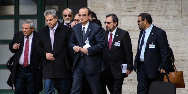 Syrian opposition chief negotiator Hadi al-Bahra (C) smokes a cigarette as he walks with a delegation outside the United Nations Offices on the second day of face-to-face peace talks in Geneva on January 26, 2014. Syria's regime and opposition are expected to discuss prisoner releases on the second day of face-to-face peace talks in Geneva. With no one appearing ready for serious concessions, mediators are focusing on short-term deals to keep the process moving forward, including on localised ceasefires, freer humanitarian access and prisoner exchanges. AFP PHOTO / FABRICE COFFRINI (Photo credit should read FABRICE COFFRINI/AFP/Getty Images)