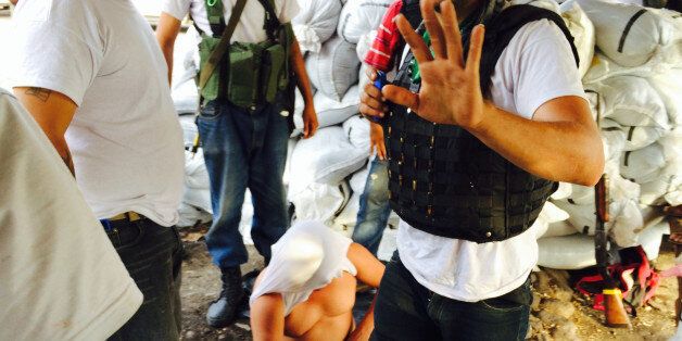 LA ESTACION, MEXICO--January 15, 2013: Militiamen interrogate a man they suspected of working for the Knights Templar drug cartel.