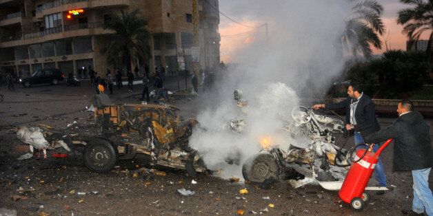 Lebanese extinguish a minibus in fire at the site of an explosion on February 3, 2014 in Choueifat, south of the capital Beirut. A suicide bomber detonated an explosive belt inside the minibus, wounding two people, medical and government officials said. Choueifat lies south of Beirut, not far from the suburbs of the city, which have been targeted in multiple bomb attacks in recent months. AFP PHOTO STR (Photo credit should read -/AFP/Getty Images)