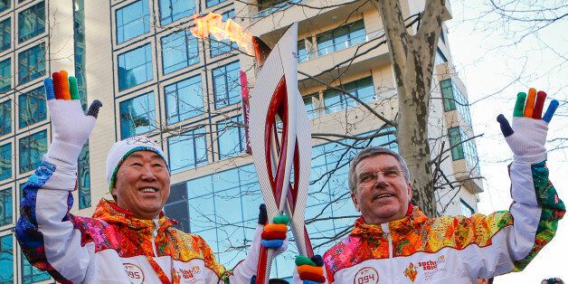 International Olympic Committee (IOC) President Thomas Bach (R) hands over the 2014 Sochi Olympics Winter Games torch to United Nations (UN) Secretary-General Ban Ki-moon as the torch relay arrived in Sochi on February 6, 2014, on the eve of the games' opening ceremony. AFP PHOTO / POOL / SHAMIL ZHUMATOV (Photo credit should read SHAMIL ZHUMATOV/AFP/Getty Images)