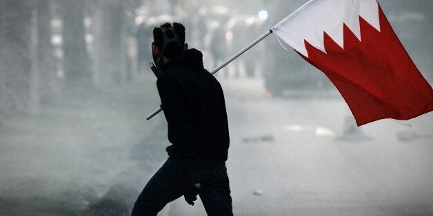 A Bahraini protester holds his national flag during clashes with riot police following the funeral of 20-year-old prisoner Fa
