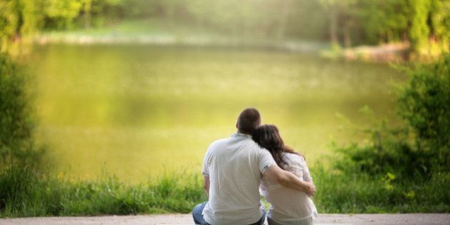 Caucasian couple sitting on bench hugging by