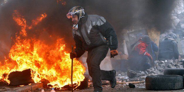 A Anti-government protesters runs past flames during clashes with the police in the center of Kiev on February 20, 2014. Armed protesters stormed police barricades in Kiev on Thursday in renewed violence that left at least 17 people dead and shattered an hours-old truce as EU foreign ministers held crisis talks with Ukraine's embattled president. AFP PHOTO/ SERGEI SUPINSKY (Photo credit should read SERGEI SUPINSKY/AFP/Getty Images)