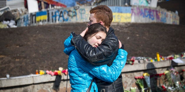 KIEV, UKRAINE - FEBRUARY 24: A young couple comfort each other beside floral tributes in Independence Square to the anti-government demonstrators who were killed in clashes with police last week on February 24, 2014 in Kiev, Ukraine. Ukrainian interim interior minister has today announced that an arrest warrant has been issued for ousted President Viktor Yanukovych. (Photo by Rob Stothard/Getty Images)