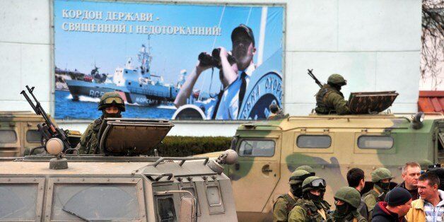 Unidentified men in military fatigues stand in front of a poster reading ' The border of the country - is sacred and untouchable' as they block a base of the Ukrainian frontier guard unit in Balaklava on March 1, 2014. Ukraine's border guard service said that about 300 armed men were attempting to seize its main headquarters in the Crimean port city of Sevastopol under orders from Russian Defence Minister Sergei Shoigu. AFP PHOTO/ VIKTOR DRACHEV (Photo credit should read VIKTOR DRACHEV/AFP/Getty Images)