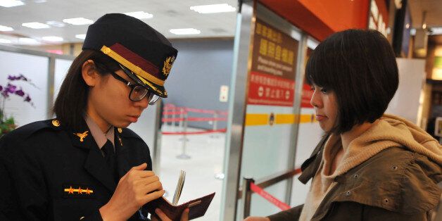 An airport security officer (L) checks a passenger's passport and boarding pass at Taipei Songshan Airport on March 10, 2014. Malaysia has said it is looking at a possible terror motive in the Malaysia Airlines plane's disappearance after at least two people used stolen passports to pass security at Kuala Lumpur International Airport (KLIA). AFP PHOTO / Mandy CHENG (Photo credit should read Mandy Cheng/AFP/Getty Images)