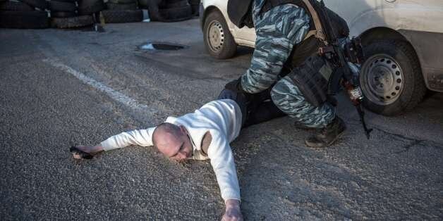 A Pro-Russian serviceman searches a man at Chongar checkpoint blocking the entrance to Crimea on March 10, 2014. Russia vowed