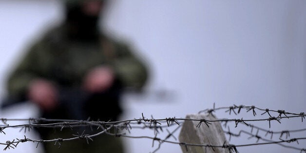 An armed man, believed to be a Russian serviceman, stands guard outside an Ukrainian military base in Perevalnoye on March 13