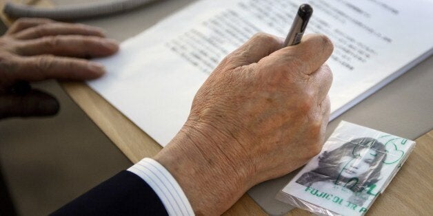 Shigeo Iizuka of the Association of the Families fo Victims Kidnapped by North Korea (AFVKN) holds a pen as a picture of his