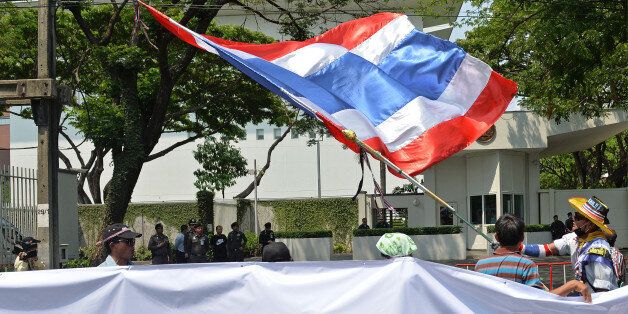 An anti-government protestor waves the Thai flag during a rally staged outside the United States embassy in Bangkok on 6 March, 2014. Twenty-three people -- including four children -- have died in political violence since the street movement began at the end of October, fuelling fears of a wider civil conflict. AFP PHOTO/Manjunath KIRAN (Photo credit should read Manjunath Kiran/AFP/Getty Images)