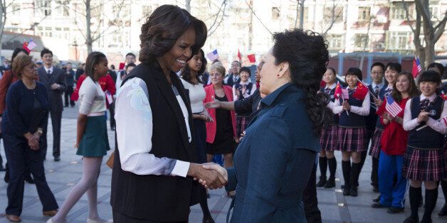 BEIJING, CHINA - MARCH 21: U.S. first lady Michelle Obama, left, is greeted by Peng Liyuan, wife of Chinese President Xi Jinping upon arrival for a visit to the Beijing Normal School, a school that prepares students to attend university abroad, March 21, 2014 in Beijing, China. Michelle Obama's one-week-long visit in China will be focused on educational and cultural exchanges. (Photo by Andy Wong-Pool/Getty Images)
