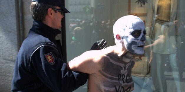 A police officer prevents a Femen activist disguised as a skeleton from staging a protest against an anti-abortion demonstration 'Si a la Vida' near the Puerta del Sol square in Madrid, on the International life day on March 23, 2014. AFP PHOTO / CURTO DE LA TORRE (Photo credit should read CURTO DE LA TORRE/AFP/Getty Images)