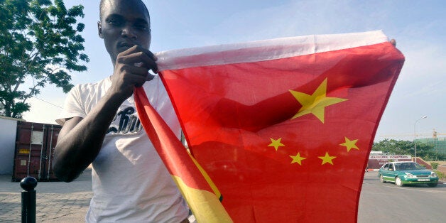 A man poses with Congo and China flags on March 28, 2013 , in Brazzaville on the eve of the visit from China's new President Xi Jinping. AFP Photo/ Junior D.Kannah (Photo credit should read JUNIOR D.KANNAH/AFP/Getty Images)