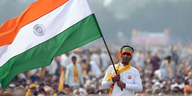 An Indian supporter of the Bharatiya Janata Party (BJP) Prime Ministerial candidate for India's forthcoming general election and Chief Minister of the western Indian state of Gujarat Narendra Modi and Indian yoga guru Baba Ramdev waves the national flag during the 'Yoga Mahotsav' event run by Ramdev and attended by Modi in New Delhi on March 23, 2014. Ramdev is launching a 'Yoga Mahotsav' across India with millions of people scheduled to take part in yoga sessions including Bharatiya Janata Party (BJP) Prime Ministerial candidate for India's forthcoming general election and Chief Minister of the western Indian state of Gujarat Narendra Modi. India, the world's biggest democracy, announced the start of national elections on April 7 that are expected to bring Hindu nationalist Narendra Modi to power on a platform of economic revival. AFP PHOTO /SAJJAD HUSSAIN (Photo credit should read SAJJAD HUSSAIN/AFP/Getty Images)