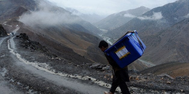 An Afghan villager carries election materials over his shoulders as he hikes back to his village along a country road high in the mountains of Shutul District in northern Afghanistan on April 4, 2014. Afghans will vote on April 5 in the country's third presidential election to choose a successor to Hamid Karzai, who has led the country since the fall of the Taliban in 2001. AFP PHOTO/SHAH MARAI (Photo credit should read SHAH MARAI/AFP/Getty Images)