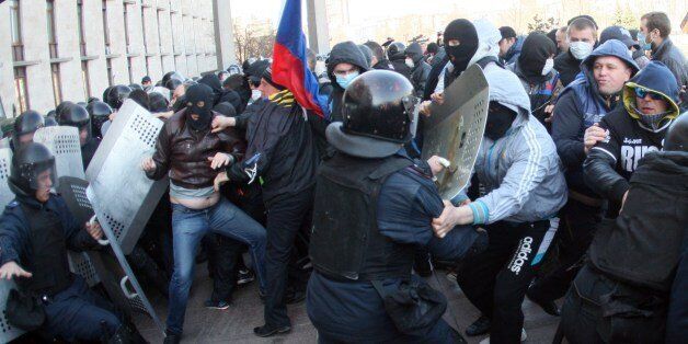 Pro-Russian supporters clash with members of the riot police as they storm the regional administration building in the eastern Ukrainian city of Donetsk on April 6, 2014. About 50 protesters chanting 'Donetsk is a Russian city!' broke through police lineson April 6 and stormed inside the main administration building of the eastern Ukrainian city. The activists moved away from a crowd of about 2,000 rallying on the main city square and threw firecrackers at police surrounding the government seat before raising the Russian flag above the 11-storey building. AFP PHOTO/ ALEXANDER KHUDOTEPLY (Photo credit should read Alexander KHUDOTEPLY/AFP/Getty Images)