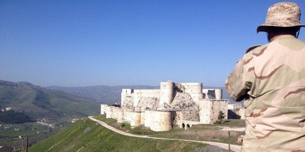 A government soldier looks out over the renowned Crusader castle Krak des Chevaliers near the Syria-Lebanon border after forces loyal to Syria's President Bashar al-Assad seized the fortress on March 20, 2014 marking a significant advance in their drive to seal the Lebanese border and sever rebel supply lines. Lebanon's Al-Mayadeen TV, a private broadcaster sympathetic to Syria's government, broadcast live images showing regime forces atop one of the castle's towers, raising the Syrian government flag. AFP PHOTO / SAM SKAINE (Photo credit should read SAM SKAINE/AFP/Getty Images)