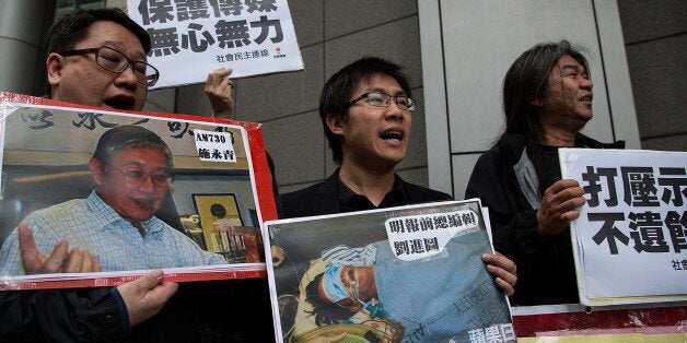 HONG KONG - FEBRUARY 27: Pro-democracy activists hold a sign with an image of former chief editor of the Ming Pao daily Kevin Lau Chun-to as they protest outside the police headquarters on February 27, 2014 in Hong Kong. The former chief editor of the Ming Pao newspaper, Lau has undergone surgery on a lung and on his legs after being stabbed by an armed assailant, who fled with an accomplice on a motorcycle. (Photo by Lam Yik Fei/Getty Images)