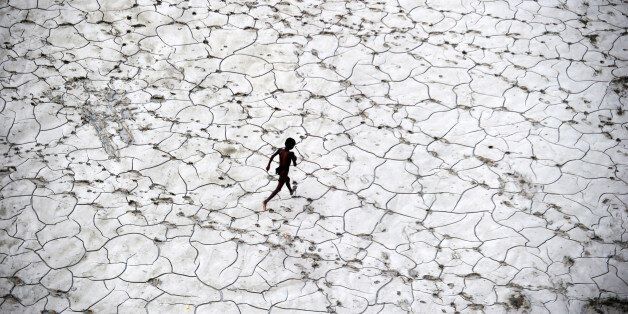 An Indian street child plays in a dry river bed after flood waters receded in Allahabad on October 25, 2013. AFP PHOTO/ SANJAY KANOJIA (Photo credit should read Sanjay Kanojia/AFP/Getty Images)