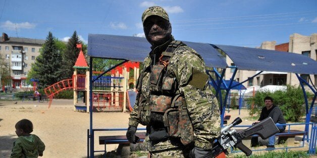 An armed man in military fatigue guards a barricade outside the regional administration building in the eastern Ukrainian cit
