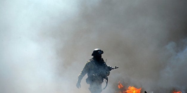 A member of the Ukrainian special forces takes position at an abandoned roadblock in the eastern Ukrainian city of Slavyansk on April 24, 2014. Ukraine's military launched an assault on the flashpoint rebel-held town of Slavyansk, sending in armoured vehicles and a helicopter, AFP journalists in the town reported. Several armoured personnel carriers drove past an abandoned rebel roadblock in flames to take up position at the entry to the town. AFP PHOTO/KIRILL KUDRYAVTSEV (Photo credit should read KIRILL KUDRYAVTSEV/AFP/Getty Images)