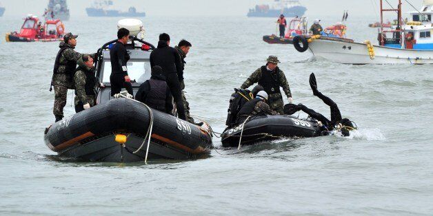 A South Korean Navy's SSU member (R) dives to rescue missing passengers of a capsized ferry at sea off Jindo on April 19, 2014. Investigators on April 19 arrested the captain accused of abandoning the South Korean ferry that capsized three days ago with 476 people on board, as divers finally accessed the submerged vessel and spotted bodies inside. AFP PHOTO / JUNG YEON-JE (Photo credit should read JUNG YEON-JE/AFP/Getty Images)