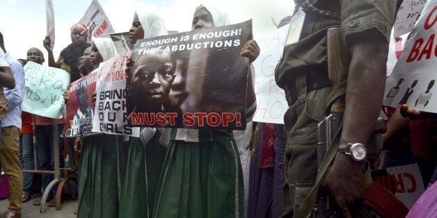 A policeman stand beside children holding as members of Lagos based civil society groups hold rally calling for the release o