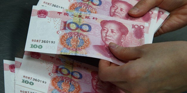 An employee counts Chinese one-hundred yuan banknotes for a photograph at the Korea Exchange Bank headquarters in Seoul, Sout