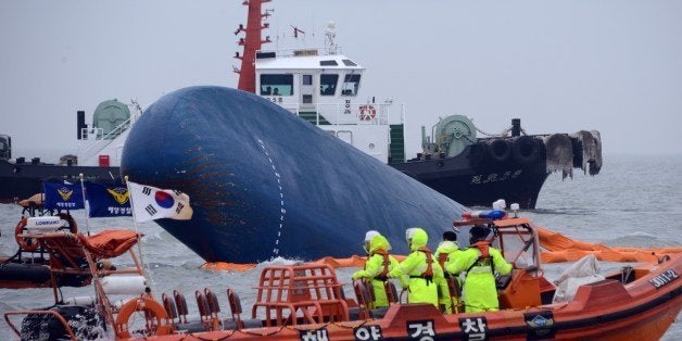 Coast guard members search for passengers near a South Korean ferry (C) that capsized on its way to Jeju island from Incheon, at sea some 20 kilometres off the island of Byungpoong in Jindo on April 17, 2014. South Korean rescue teams, including elite navy SEAL divers, raced to find up to 293 people missing from a capsized ferry carrying 459 passengers and crew -- mostly high school students bound for a holiday island. AFP PHOTO AFP PHOTO / ED JONES (Photo credit should read ED JONES/AFP/Getty Images)