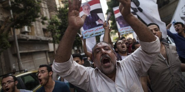 Supporters of Egyptian presidential candidate Hamdeen Sabbahi (portrait) shout slogans during a campaign rally in Cairo, on May 23, 2014. Sabbahi, 60, who says he was jailed 17 times under former presidents Anwar Sadat and Mubarak, came third in the 2012 presidential election which was won by the Islamist Mohamed Morsi. AFP PHOTO/MAHMOUD KHALED (Photo credit should read MAHMOUD KHALED/AFP/Getty Images)