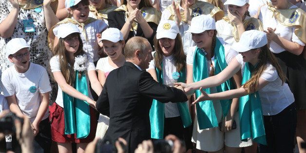 SAINT PETERSBURG, RUSSIA - MAY 24: Russian President Vladimir Putin greets young choir singers during a welcoming concert on May 24, 2014 in Saint Petersburg, Russia. The giant choir of an estimated 5000 singers sang popular Soviet songs near the St. Isaak Cathedral in Saint Petersburg, Russia. (Photo by Sasha Mordovets/Getty Images)