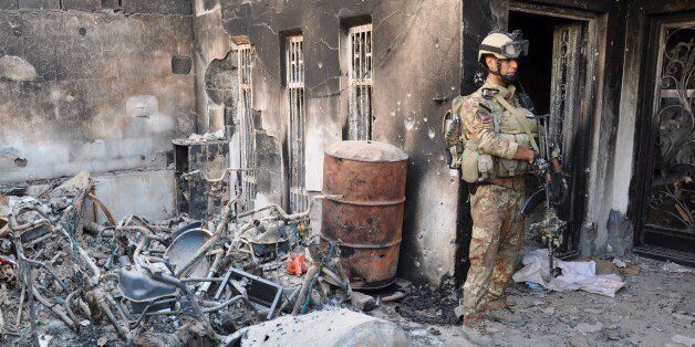A member of the Iraqi security forces stands outise a burnt house during fighting with anti-government fighters on May 21, 2014 in the city of Ramadi, west of the capital Baghdad in the Anbar province. For more than four months, anti-government fighters have held control over Fallujah, which lies just a short drive from Baghdad, and shifting parts of Anbar provincial capital Ramadi. AFP PHOTO / AZHAR SHALLAL (Photo credit should read AZHAR SHALLAL/AFP/Getty Images)
