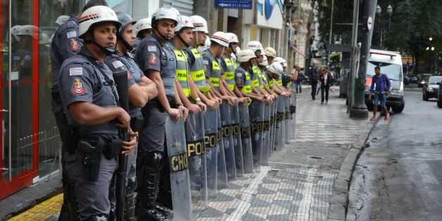 SAO PAULO, BRAZIL - May 24: Brazilian policemen stand guard as demonstrators take part in a protest against the World Cup in central Sao Paulo, Brazil on May 24, 2014. Demonstartors protested against money spent on the preparations for the upcoming World Cup which is set to begin in Brazil in less than three weeks, and demanded a general strike on the opening day of the World Cup on June 12, 2014. (Photo by Ben Tavener/Anadolu Agency/Getty Images)