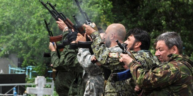 Pro-Russian militants fire Kalashnikov assault rifle during the funeral of Vasily Burov, 46, at a cemetery in the eastern Ukrainian city of Makiyivka, near Donetsk, on May 31, 2014. Burov was killed in combat with Ukrainian troops in Gorlovka, a small city in the Donetsk region, on May 29. Ukraine accused Russia on on may 31 of unleashing a mass propaganda campaign to persuade global powers not to recognise an election that gave the presidency to a pro-Western tycoon. AFP PHOTO/ VIKTOR DRACHEV (Photo credit should read VIKTOR DRACHEV/AFP/Getty Images)