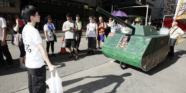 HONG KONG - JUNE 01: A Pro-democracy activist re-enacts an iconic moment from the pro-democracy movement protests of 1989, when a young man blocked the path of Chinese tanks, during a march marking the 25th anniversary of the Tiananmen Square massacre on June 1, 2014 in Hong Kong. The march marked the 25th anniversary of the bloody crackdown on the student-led pro-democracy movement protestors in Tiananmen square by Chinese soldiers, also known as the Tiananmen Square massacre. (Photo by Jessica Hromas/Getty Images)