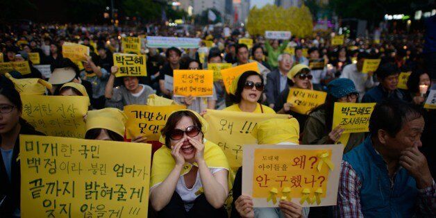 People shout slogans at a rally prior to a vigil for victims of the Sewol ferry and denouncing the government response to the disaster, in Seoul on May 24, 2014. South Korean prosecutors offered a cash reward of almost 50,000 USD on May 22 for information on a fugitive billionaire wanted in a probe into last month's ferry disaster that killed hundreds. AFP PHOTO / Ed Jones (Photo credit should read ED JONES/AFP/Getty Images)