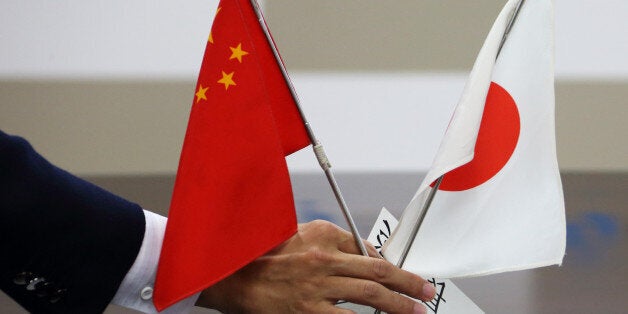 A staff member of Japan's minister of economy, trade and industry, arranges Chinese and Japanese flags before a meeting betwe