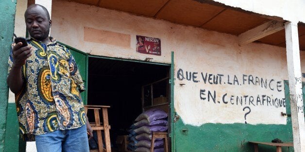 A Muslim shopkeeper uses a mobile phone in front of his shop bearing the inscription 'What does France want in Central Africa