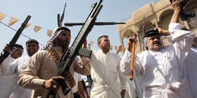 Iraqi tribes men carry their weapons as they gather, volunteering to fight along side the Iraqi security forces against Jihadist militants, on June 14, 2014, in the capital Baghdad. Leading Shiite cleric Grand Ayatollah Ali al-Sistani urged Iraqis on June 13 to take up arms against Sunni militants marching on Baghdad, as thousands volunteered to bolster the capital's defences. AFP PHOTO/ALI AL-SAADI (Photo credit should read ALI AL-SAADI/AFP/Getty Images)