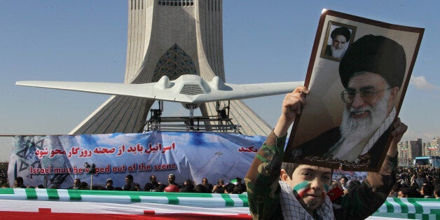 An Iranian boy holds a portrait of supreme leader, Ayatollah Ali khamenei as he walks past a replica of the captured US RQ-170 drone on display next to the Azadi (Freedom) tower during the 33rd anniversary of the Islamic revolution in Tehran on February 11, 2012. iranian President mahmoud Ahmadinejad said that Iran has broken the 'idol' of the Holocaust underpinning the creation of the Israeli state and US hegemony. AFP PHOTO/ATTA KENARE (Photo credit should read ATTA KENARE/AFP/Getty Images)