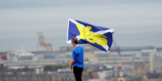 A pro-independence supporter holds a Saltire flag with 'Yes' written on it in Edinburgh on September 21, 2013 during a march