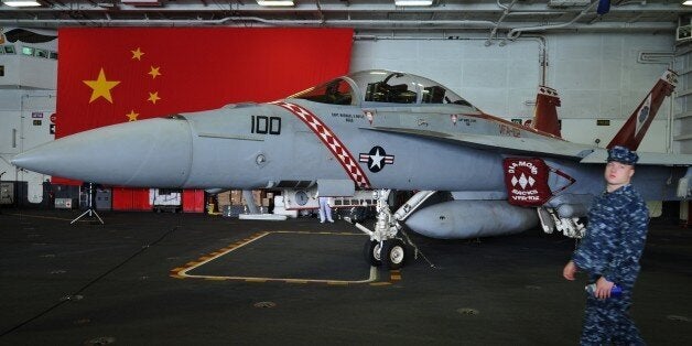 A US navy serviceman walks past an F/A-18 Hornet warplane onboard the USS George Washington, a nuclear powered aircraft carri