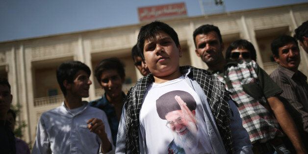 TEHRAN, IRAN - JUNE 04: A boy shows off his t-shirt with the visage of Iran's supreme leader Ayatollah Ali Khamenei outside the shrine to the Ayatollah Khomeini on the 25th anniversary of his death on June 4, 2014 on the outskirts of Tehran, Iran. Khomeini, the founder of the Islamic Republic, is still revered by many Iranians, and his portrait hangs throughout the country. (Photo by John Moore/Getty Images)