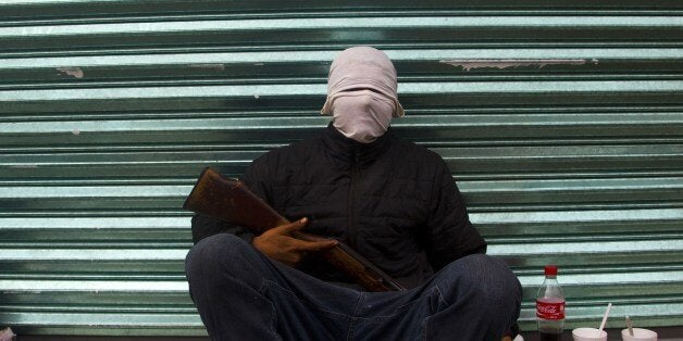 Armed members of the citizens' self-protection police sits on the street in Uspero community, Michoacan State, Mexico, on Jan
