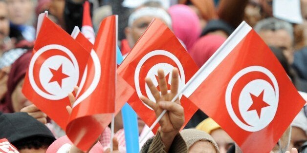 Tunisians wave their national flag and flash the four finger symbol known as 'Rabaa', which means four in Arabic, which is associated with those killed in the crackdown on the Rabaa al-Adawiya protest camp in Cairo last year as they attend a rally marking the third anniversary of the uprising that ousted long-time dictator Zine El Abidine Ben Ali on January 14, 2014 in Habib Bourguiba Avenue in Tunis. Tunisia celebrated the third anniversary of the overthrow of a decades-old dictatorship in the first Arab Spring uprising, but political divisions have hampered the adoption of a new constitution by this symbolic deadline. AFP PHOTO / FETHI BELAID (Photo credit should read FETHI BELAID/AFP/Getty Images)