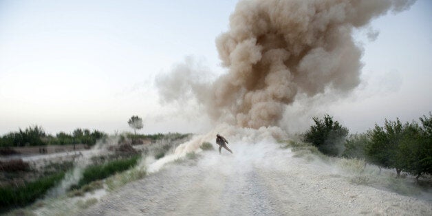 US Marine Sergeant Anthony Zabala of 1st Combat Engineering Battalion of 2nd Marine Expeditionary Brigade runs to safety as an Improvised Explosive Device (IED) explodes in Garmsir district of Helmand Province on July 13, 2009. A foot patrol was advancing painstakingly with metal detectors and bare hands to defuse bombs planted on a rough track when an explosion shot a cloud of dust and rocks into the sky in southern Afghanistan's Helmand province at dusk, killing Sergeant Michael W. Heede Junior and Staff Sgt. David S. Spicer. The unit has been in Afghanistan only months, part of a surge of 21,000 extra US troops sent to quell a Taliban insurgency that is testing Western military endurance and shows signs of expanding beyond southern and eastern heartlands. AFP PHOTO/Manpreet ROMANA (Photo credit should read MANPREET ROMANA/AFP/Getty Images)