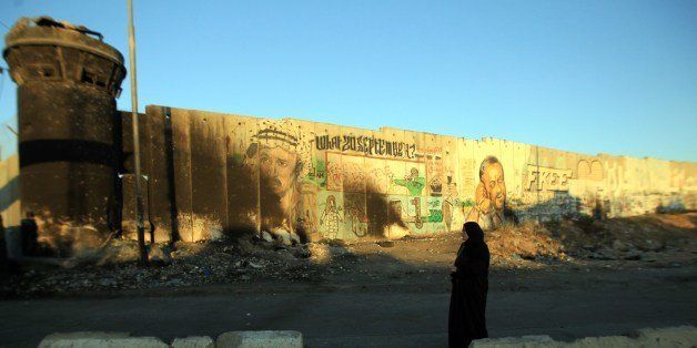 A woman walks past the Israeli built controversial separation barrier as she makes her way to the Qalandia checkpoint to cross into Jerusalem to take part in the Friday noon prayers at the Al-Aqsa mosque compound, on the second Friday of the holy Muslim fasting month of Ramadan, on July 11, 2014. Israeli warplanes kept up deadly raids on Gaza but failed to stop Palestinian militants firing rockets across the border, as the United States offered to help negotiate a truce. AFP PHOTO / Abbas MOMANI (Photo credit should read ABBAS MOMANI/AFP/Getty Images)